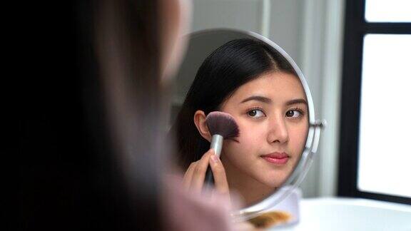 一个亚洲女人在浴室镜子前化妆