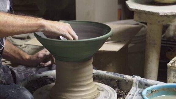 特写中年男子的手制作陶瓷接受者成型粘土使用陶艺轮