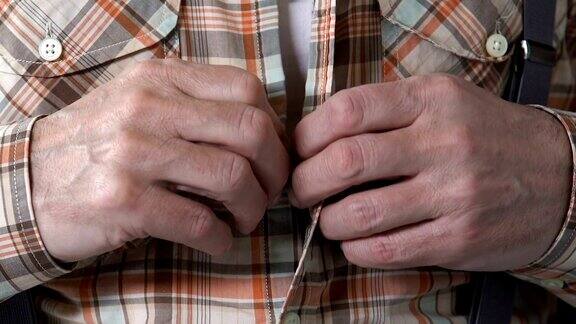 男性退休老人用颤抖的手扣上衬衫帕金森震颤症