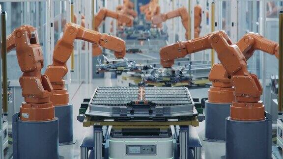 橙色机械臂自动化生产线的延时拍摄用于汽车工业组装的电动汽车电池组电动汽车智能工厂配备机械臂的电池生产线