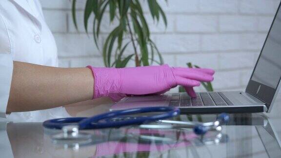 戴着手套在笔记本电脑上工作的医生