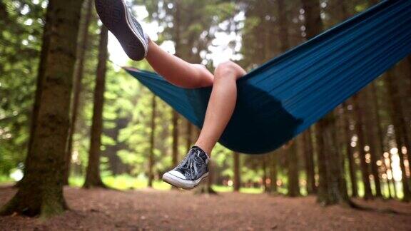 无忧无虑的女孩躺在一张吊床上享受着森林里的一天