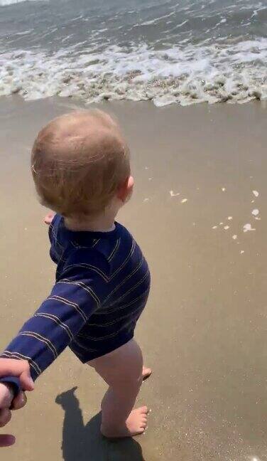 欢快的小女孩牵着妈妈的手走向海边的水