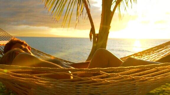 日落时分浪漫的情侣在热带吊床上放松夏天豪华度假