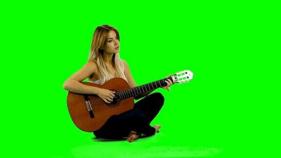 年轻美丽的白人女子在随意弹吉他绿屏