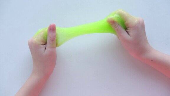 女孩把绿色的粘液往两边伸展孩子们用手玩黏液玩具把粘液弄成白色时髦的液体玩具粘在手和手指上4k的片段