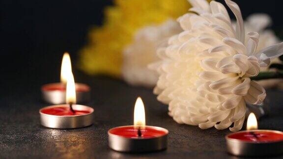 清明节墓碑上的菊花和点燃的蜡烛