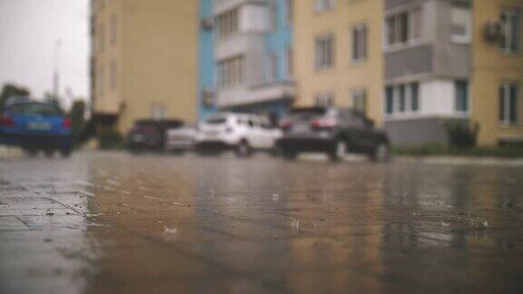 雨水坑雨下在停车场院子里特写镜头雨点落在潮湿的街道瓷砖上外面下着雨小区的院子里夏天阵雨