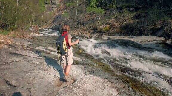 女背包客走在岩石上探索高山峡谷瀑布
