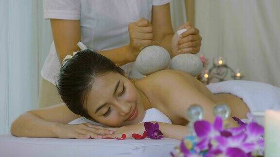 美丽的亚洲女人享受泰国草药按压按摩治疗