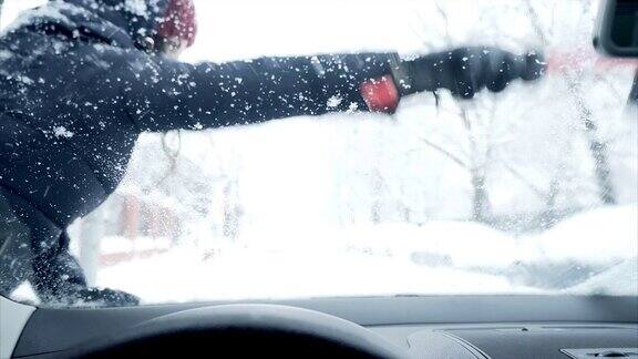 一个女人在刮汽车挡风玻璃上的雪