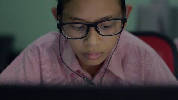 肖像可爱的亚洲年轻女孩戴着耳机从笔记本学习在线课程严重的女性青少年通过家庭使用电脑上网