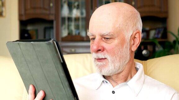 现代老年人在家用平板电脑浏览阅读新闻退休后活跃的现代生活