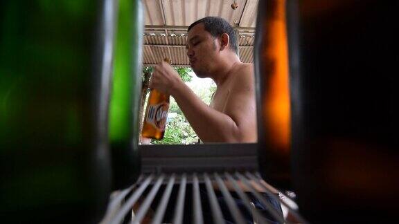 从冰箱里拿出啤酒的亚洲人