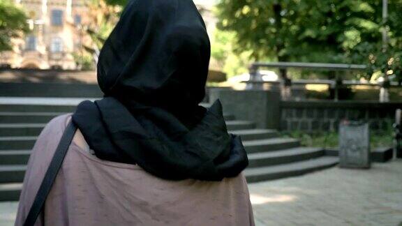 夏天的白天年轻平静的穆斯林女孩戴着头巾走上公园楼梯的剪影宗教概念城市概念
