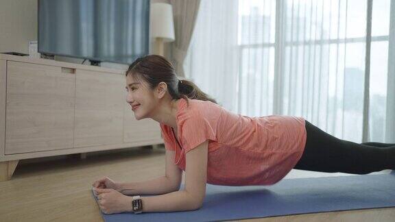 新冠肺炎疫情期间亚洲女性在家中客厅锻炼时很开心
