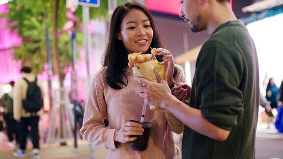 SLOMO手持中景拍摄一对年轻夫妇在香港吃传统街头小吃