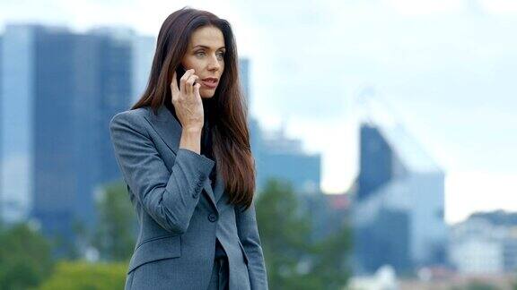 自信的商业女性在电话中解决金融危机问题她站在他的背后与摩天大楼的大城市