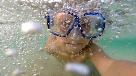 年轻女孩戴着面具在水下游泳