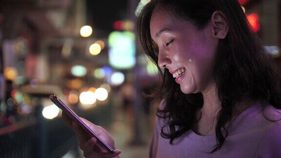 一名女子在夜街用智能手机进行社交媒体