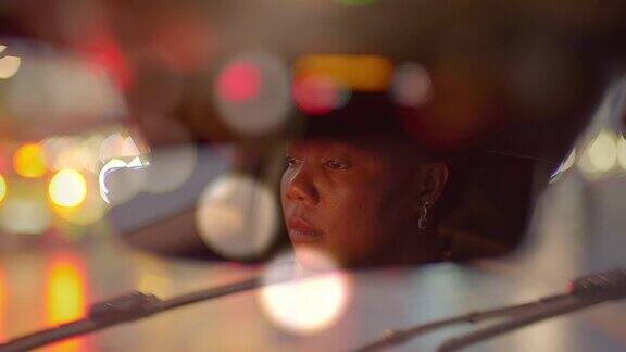 在雨中独自驾车的黑人妇女握着方向盘观察大都市夜晚的道路交通