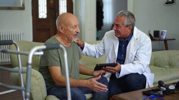医生在与年长男性患者交谈时使用平板电脑