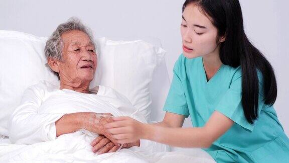 女医生牵着老太太的手安慰她老妇人正躺在床上