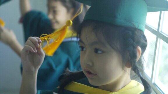 亚洲小学女生戴着毕业帽穿着毕业服站在学校里微笑着