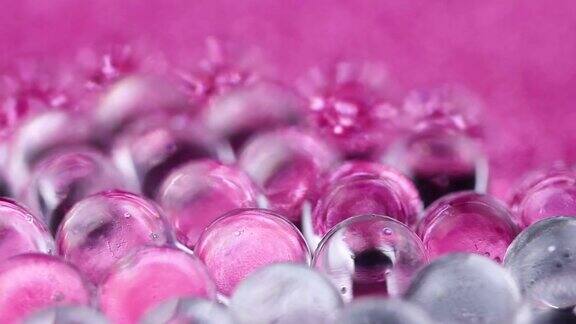 水凝胶球在粉红色和银色的表面旋转关闭宏
