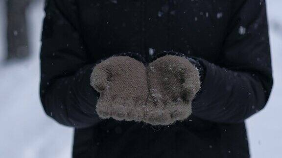 女人喜欢下雪戴着蓝色手套看着小雪花