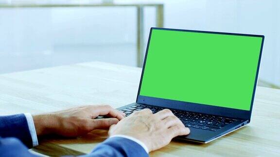 特写商人的手打字在笔记本电脑上与色度键隔离模拟绿色屏幕办公室是明亮和现代的