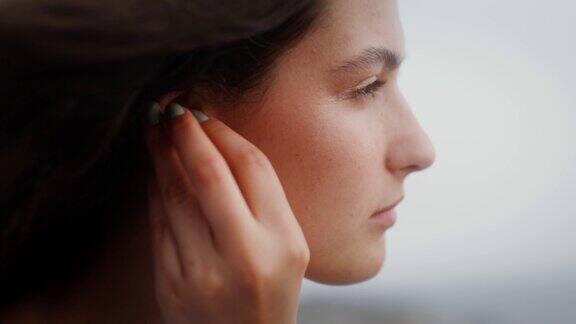 一个年轻的女人把无线耳机放在耳朵里
