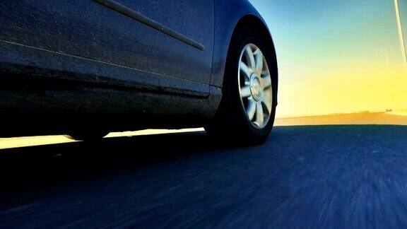 跑车行驶在狭窄的道路朝着阳光在日落低角度的观点