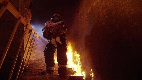 勇敢的消防员带着救下的小女孩下了燃烧的楼梯明火随处可见