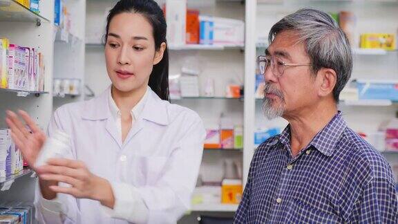 一位高级男子在药店和女药剂师交谈女药师在药房协助向老年病人客户讲解药物