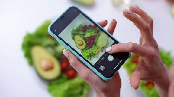 用手机的相机拍蔬菜沙拉的女人的特写