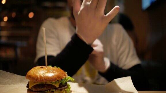 一个留着胡子的男人正戴着手套吃汉堡芝士汉堡
