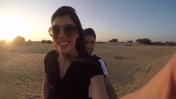 一对夫妇在沙漠里骑骆驼自拍