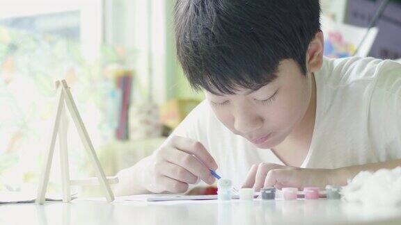 年轻的亚洲男孩微笑着在家里画水彩画
