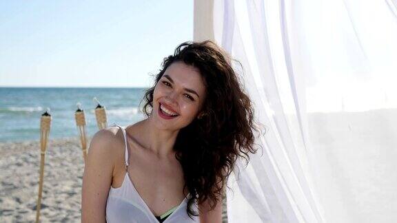 肖像美丽的女孩在海滩上快乐的女人卷着头发夏天度假的女人在海边女性美丽的脸微笑