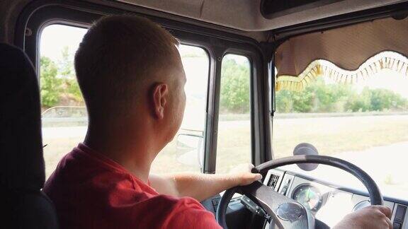 在阳光明媚的日子里卡车司机驾驶着卡车穿过乡村男子手握方向盘驾驶汽车驶向目的地在乡村公路上行驶的卡车司机物流