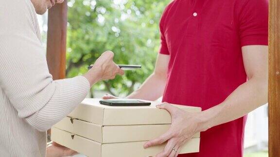 年轻的邮政快递员戴着口罩将食品盒寄给顾客并在家中通过手机二维码支付亚洲男收到快递包裹