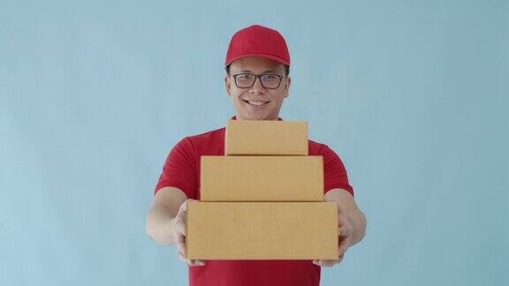 亚洲快乐快递员携带纸包盒子孤立在蓝色背景与微笑的脸邮政投递服务