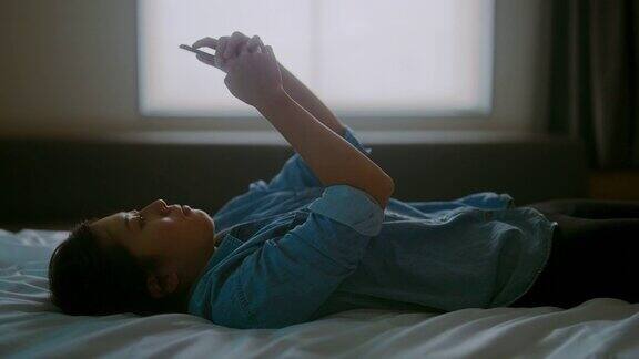 年轻女子躺在床上用智能手机