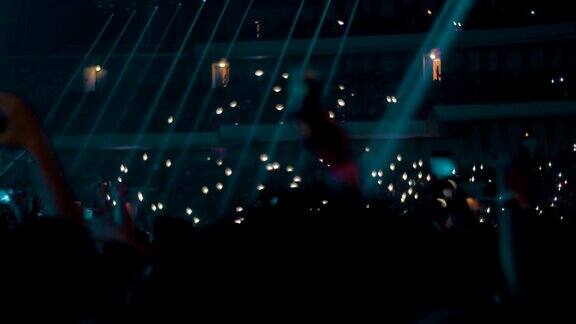 音乐爱好者在音乐厅挥舞着灯光用手机拍摄