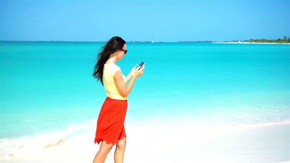年轻女子在热带海滩度假期间使用电话游客使用手机