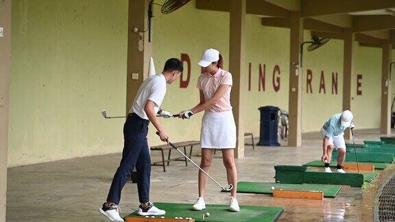 亚洲华人年轻夫妇在高尔夫练习场练习打高尔夫球