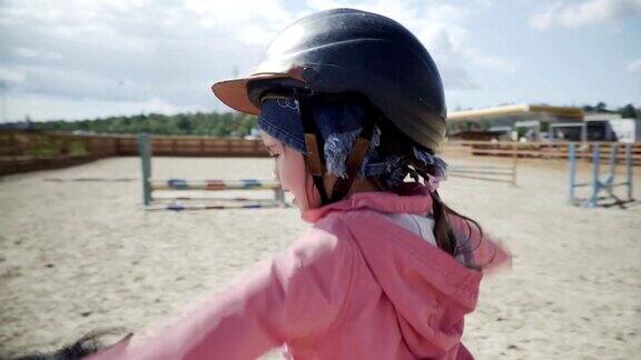 快乐的小女孩骑着一匹黑马在马术俱乐部里