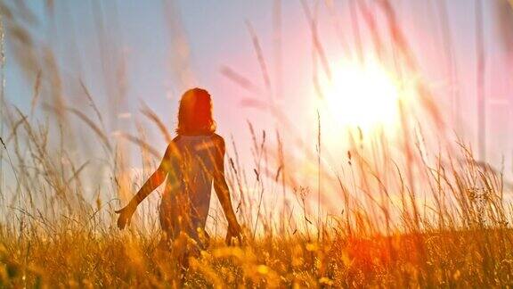 SUPERSLOMOGirl在夕阳下金色的草地上奔跑