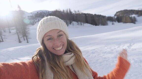 一名女子冬天在瑞士旅行在山上拍摄自拍视频肖像